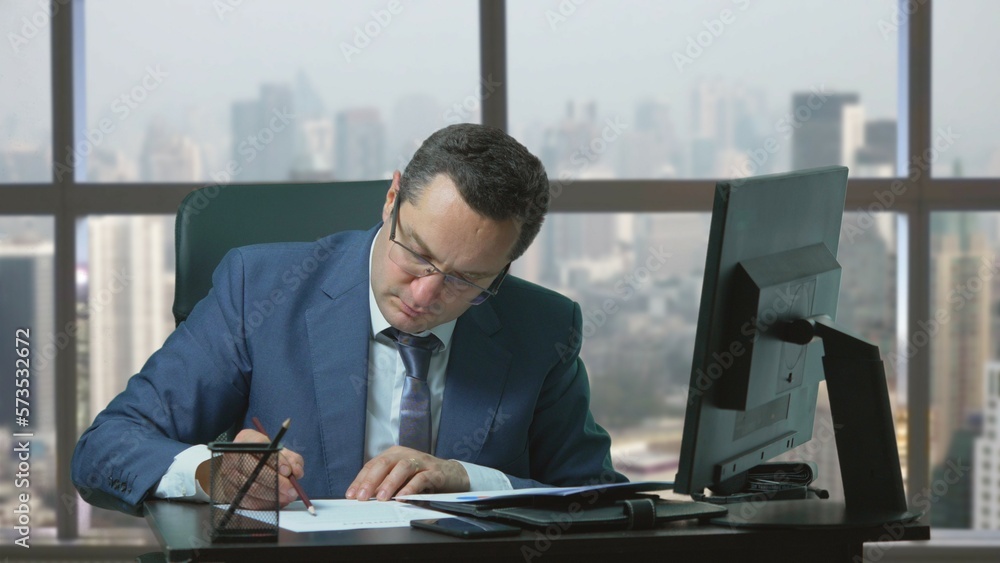 Concentrate man with suit sit desk at office and underline on paper, city view Concentrate man with suit sit desk at office and underline on paper, city view
