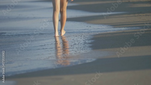Detail of child feet walking on beach sand, waves comes on shore, feeling soft