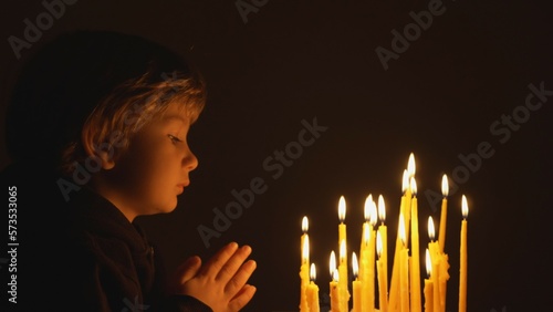 Portrait of little child praying close lightning candles, hope, spiritual