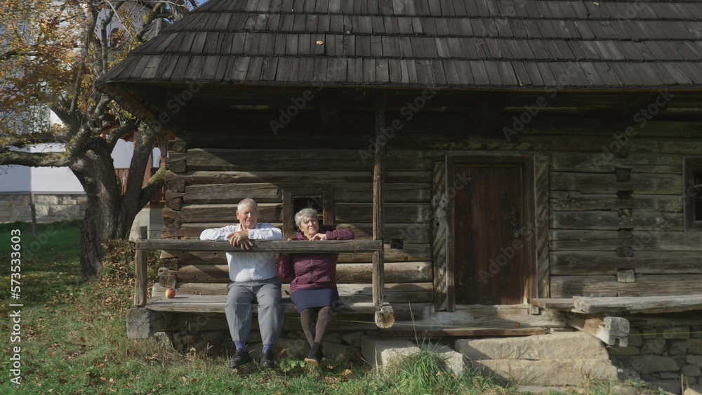 Seniors couple relax and enjoy time together on wooden rustic house porch