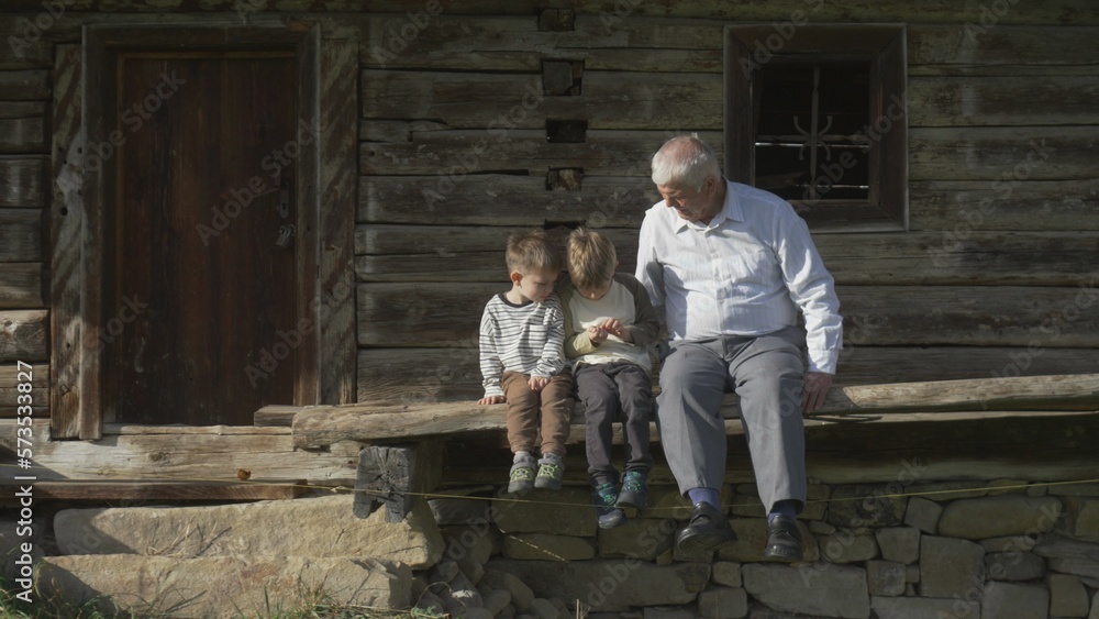 Old man and two kids on wooden porch of rustic house Old man and two kids on wooden porch of rustic house