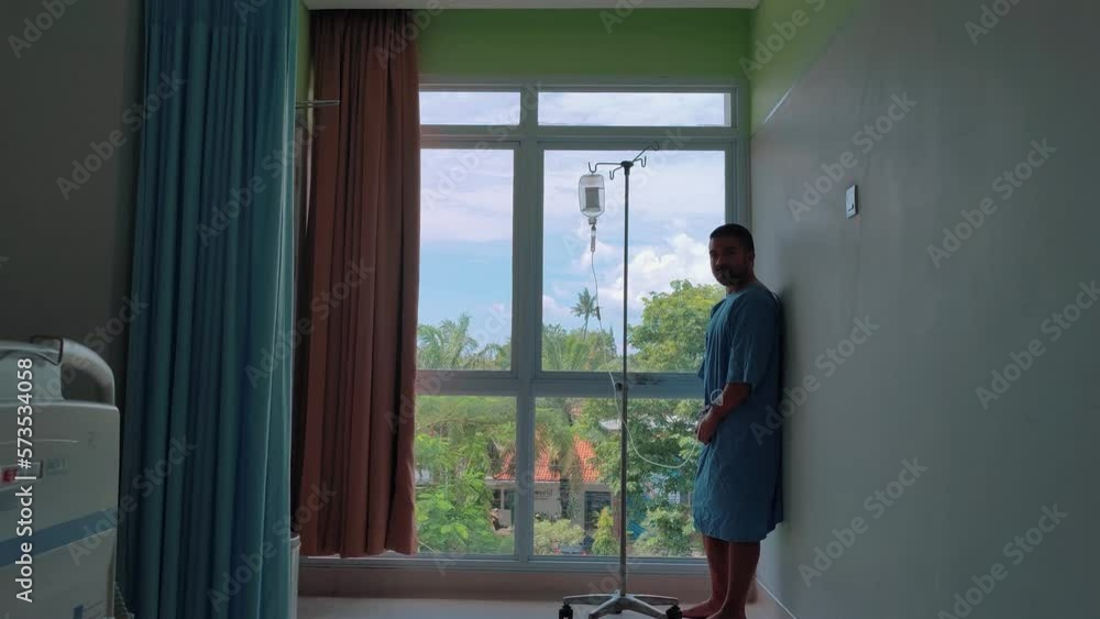 Asian Man Patient Walking Standing in Hospital Room after Undergoing Surgery with Medication Infusion Asian Man Patient Walking Standing in Hospital Room after Undergoing Surgery with Medication Infusion