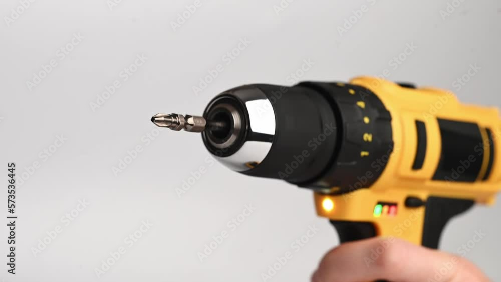 Yellow cordless electric screwdriver with a rotating bit, in hand. Close-up.Construction concept Yellow cordless electric screwdriver with a rotating bit, in hand. Close-up.Construction concept