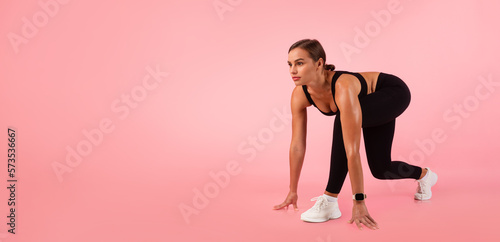 Motivated Woman Standing In Crouch Start Position Over Pink Background In Studio