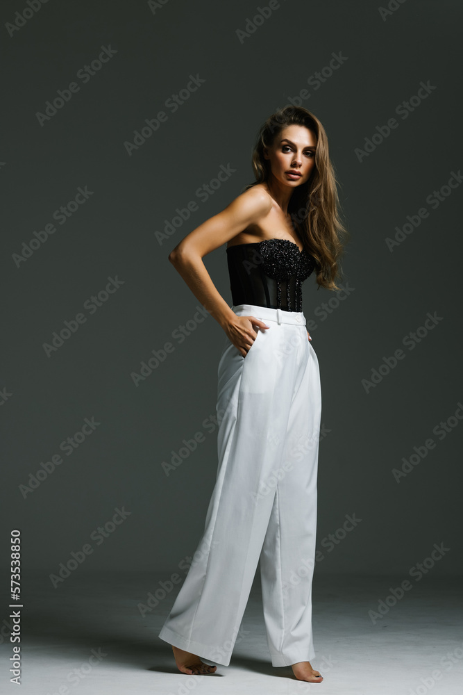 Sexy woman in black corset and black high boots. Fashion young woman with long legs posing at studio. Sexy woman in black corset and black high boots. Fashion young woman with long legs posing at studio.