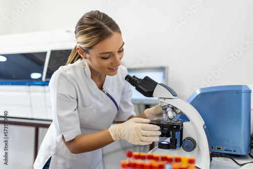 Scientist biochemist or microbiologist working research with a microscope in laboratory.