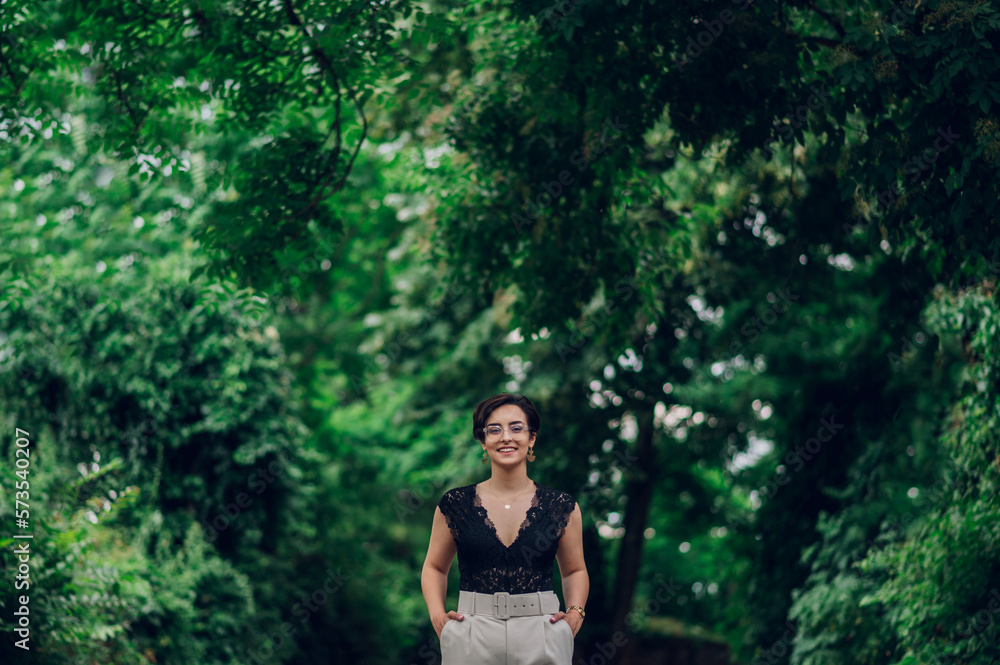 Stylish woman wearing beige pants and a black lace top walking in the nature Stylish woman wearing beige pants and a black lace top walking in the nature