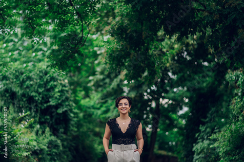 Stylish woman wearing beige pants and a black lace top walking in the nature