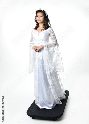 Full length portrait of beautiful woman wearing  fantasy costume, white bridal gown.  standing pose,  gestural arm movements casting a spell. Isolated white studio background.  © faestock