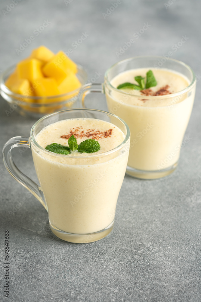 Lassi with mango. Traditional Indian drink, gray background. Summer refreshing smoothie. Side view, selective focus.
