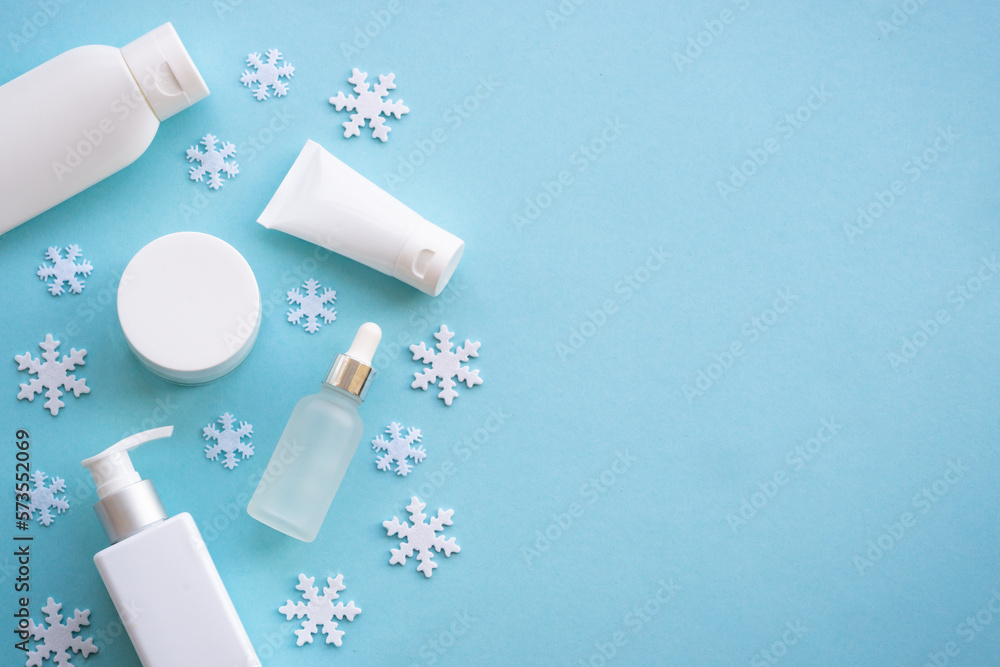 Winter cosmetic with knitting scarf on blue background. Flat lay with copy space. Winter cosmetic with knitting scarf on blue background. Flat lay with copy space.