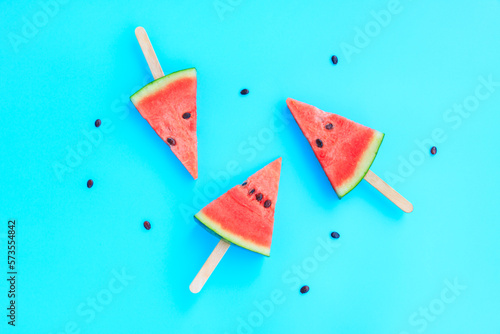Watermelon fruit sliced with wood ice cream stick on blue pastel background, Watermelon ice cream, watermelon popsicle, Summer concept © voranat