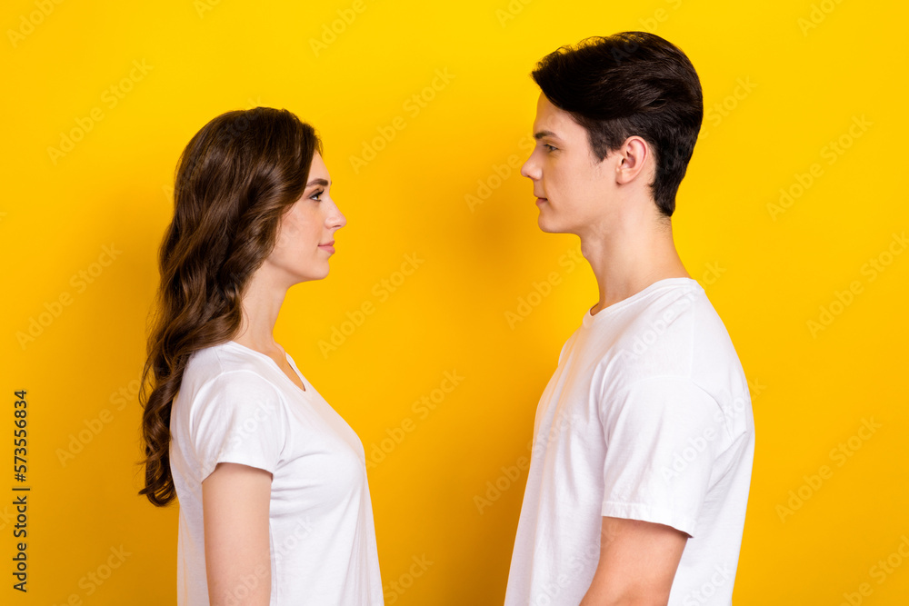 Fototapeta premium Photo of sweet pretty husband wife dressed white t-shirts standing looking each other isolated yellow color background