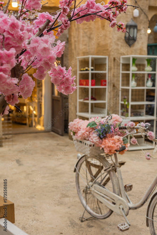 Street spring decoration. Spring sakura blossom tree, old bicycle  decorated with flowers in the old town, street with souvenir shop as background.