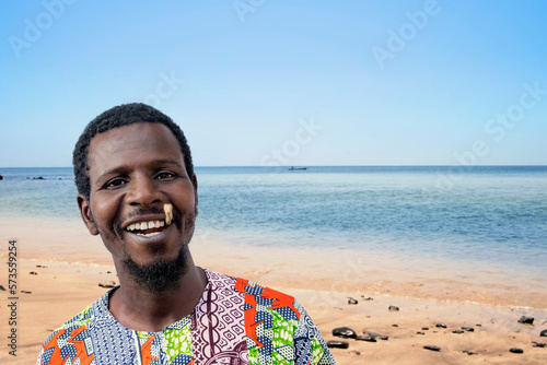 African man holding a miswak between his teeth at the beach (traditional teeth cleaning twig, also called sothio or sotio), photo photo