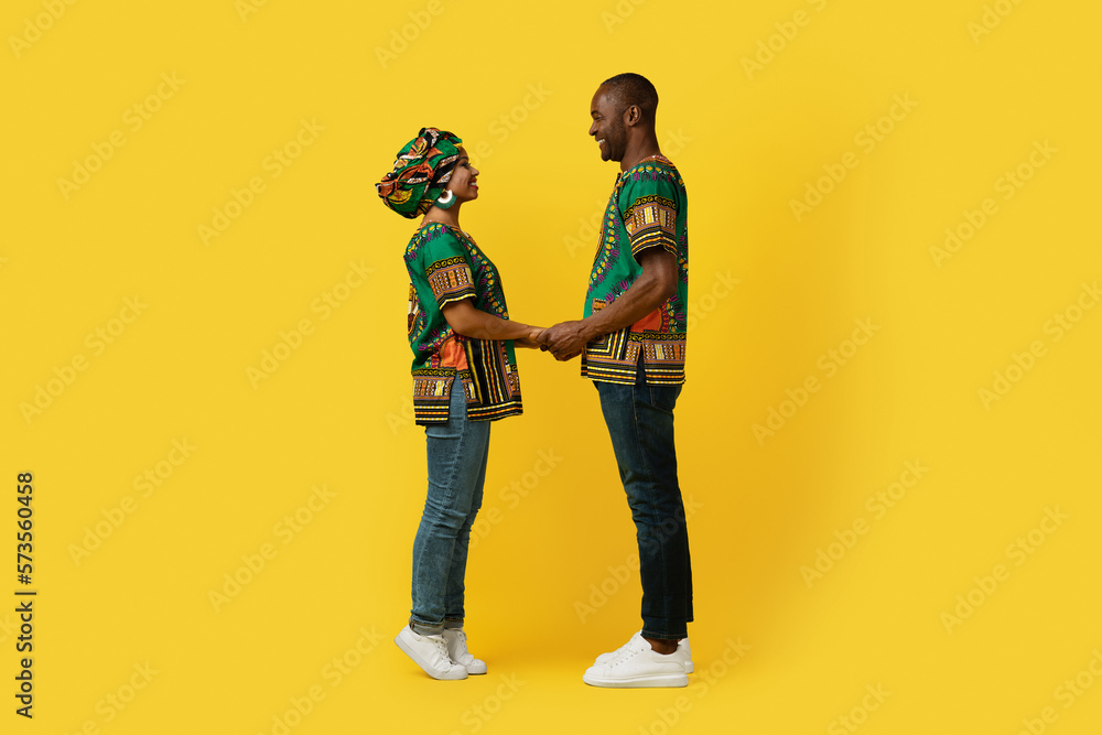 Loving black couple in national costumes bonding on yellow Loving black couple in national costumes bonding on yellow