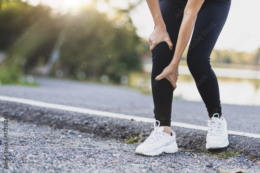 The female athlete suffered an ankle injury. A female runner has pain in her ankle. A runner sits down with a knee injury. The female athlete fell and had a bruise on her knee.