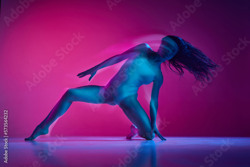 Freestyle. Sensuality. Young woman dancing in bodysuit over gradient pink studio background in neon with mixed lights. Concept of contemporary dance style, art, aesthetics, hobby, creative lifestyle