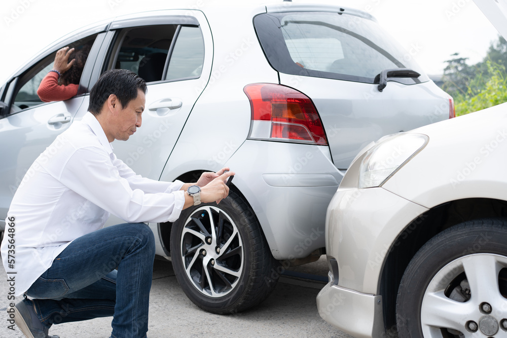 Asian men driver check for damage after a car accident before taking pictures and sending insurance. Online car accident insurance claim after submitting photos and evidence to an insurance company. Asian men driver check for damage after a car accident before taking pictures and sending insurance. Online car accident insurance claim after submitting photos and evidence to an insurance company.