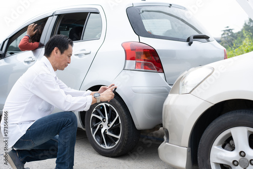 Asian men driver check for damage after a car accident before taking pictures and sending insurance. Online car accident insurance claim after submitting photos and evidence to an insurance company. © Prot