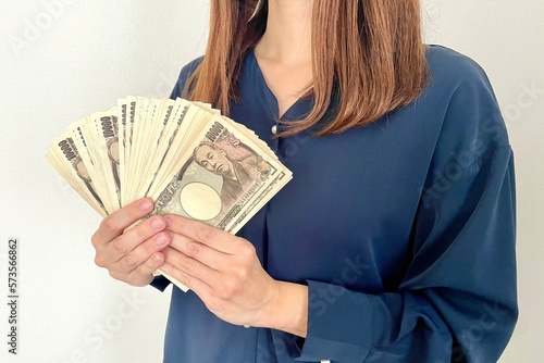 たくさんの現金を手に持つ女性 