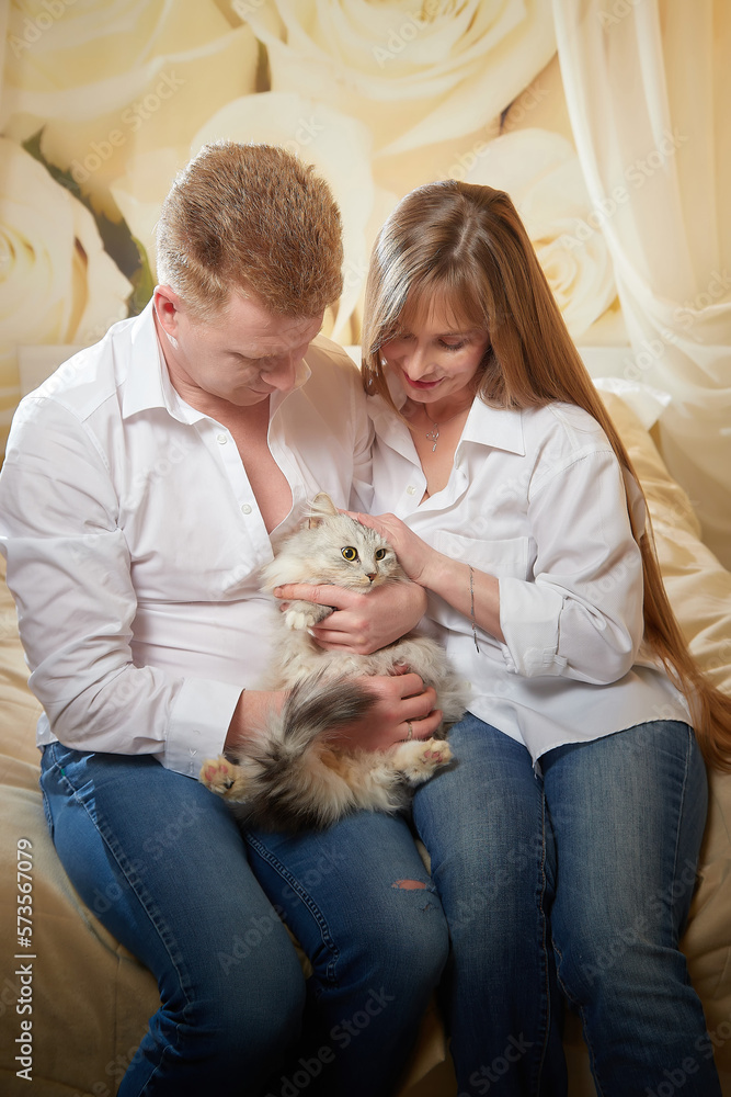 Happy loving couple with a big fat fluffy cat in the room Happy loving couple with a big fat fluffy cat in the room
