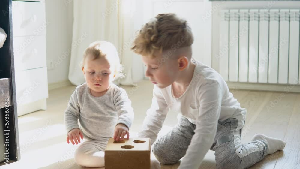 Two kids boy and girl playing with wooden shape sorter Two kids boy and girl playing with wooden shape sorter