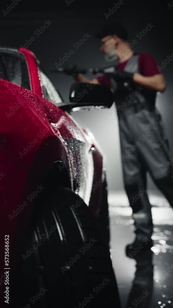Vertical Screen Car Wash Expert Using Pressure Washer to Clean a Red