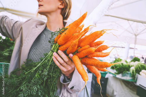 Quadro em tela Woman with organic carrots buying vegetables and greens in local market