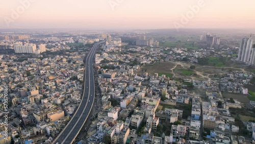 aerial drone shot flying forward over the elevanted sohna gurgaon road with vehicles passing over surrounded by densely packed houses shops and small businesses in Delhi NCR photo