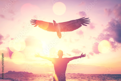 Man raise hand up on top of mountain and sunset sky with eagle birds fly abstract background. Copy space freedom travel adventure and business victory concept.