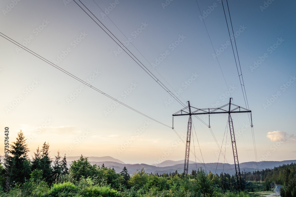 Electrical power lines and towers at at the mountain landsape. sunset.