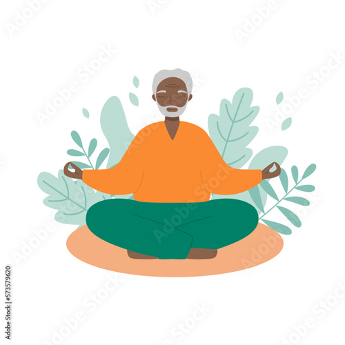 Senior man sits cross-legged and meditates with leaves background. Old man makes morning yoga or breathing exercises.
