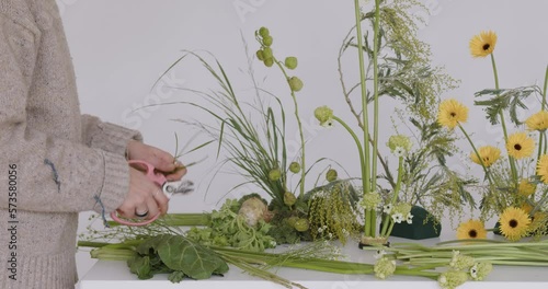 female doing new bouquet. Florist makes a floral oasis. Girl working in flower shop studio. Female florist artist cleans flowers for a beautiful bouquet, workplace view. High quality 4k footage
