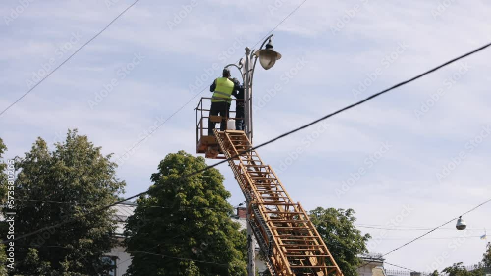 Technician on aerial, fix light, repair works. Street light repair work