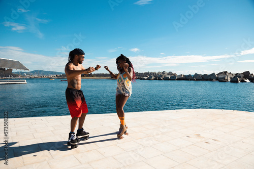 Cheerful couple roller skating outside. Fun sexy boyfriend and girlfriend enjoy in sunny day. © JustLife