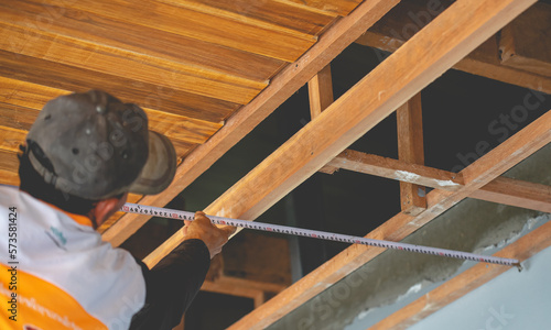 construction worker on a ladder ,Carpenter measuring tape measure installing teak ceiling