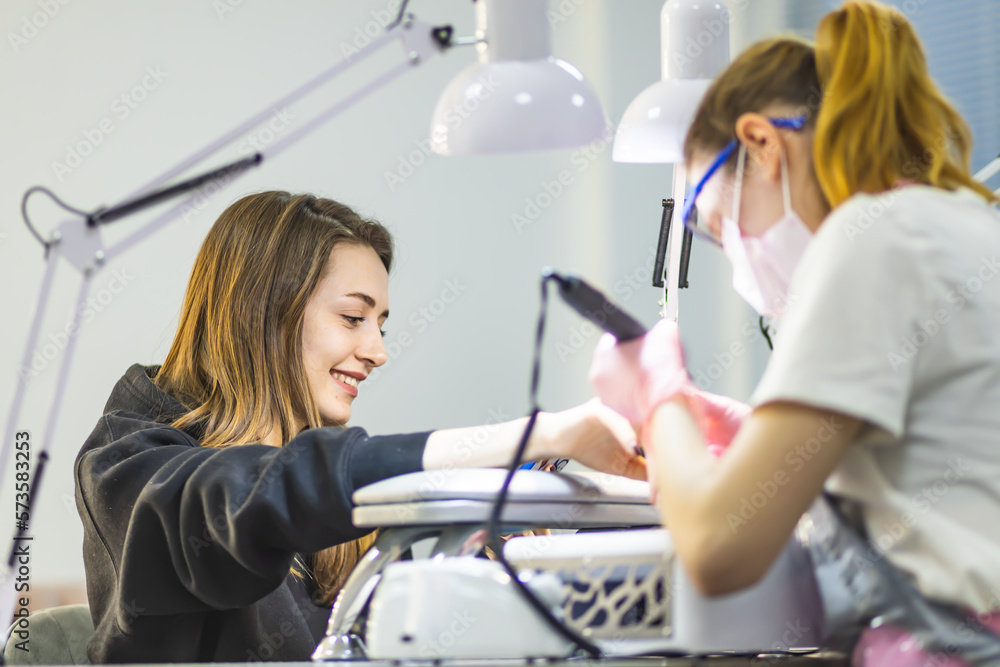 The manicurist cleans and removes the cuticle from the nail plate. Manicure process. Cut manicure technique. Special equipment for trimmed manicure. The manicurist cleans and removes the cuticle from the nail plate. Manicure process. Cut manicure technique. Special equipment for trimmed manicure.