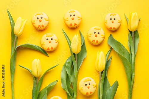 Foto Set of easter macaroon chicks with yellow tulips over yellow background