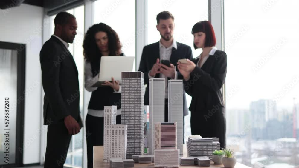 Close up of residential project maquette. Beautiful confident curly business lady showing her financial and sales report on laptop pc for her focused high-skilled multiracial business colleagues. Close up of residential project maquette. Beautiful confident curly business lady showing her financial and sales report on laptop pc for her focused high-skilled multiracial business colleagues.