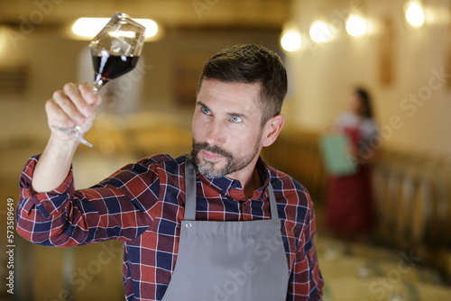 winemaker tasting red wine in cellar