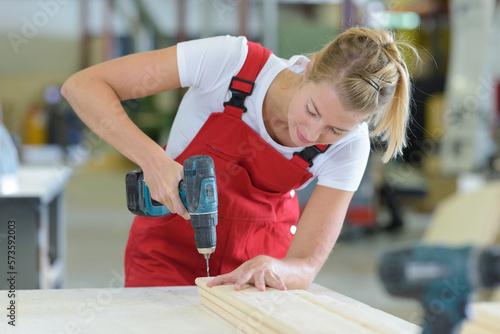 female carpenter drilling on wood