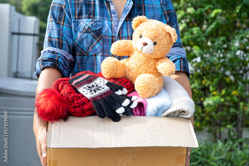 Quadro em tela Volunteer woman provide clothing donation box with used clothes and doll to support help for refugee, homeless or poor people in the world