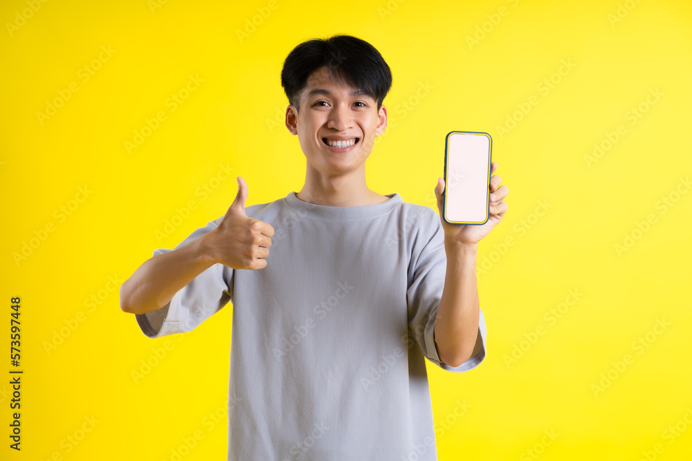 image of a handsome young man using his phone and posing on a yellow background image of a handsome young man using his phone and posing on a yellow background