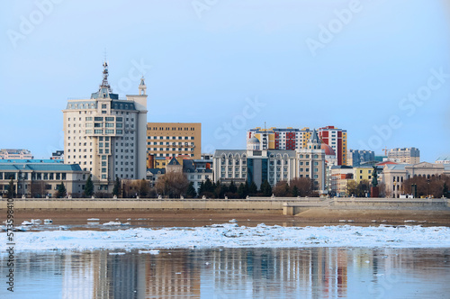 Spring ice drift on the Amur River against the backdrop of colorful buildings in the city of Heihe, China. Morning blue cloudless sky. View from the city of Blagoveshchensk, Russia.