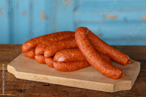 Raw Sausage on wooden board in different compositions and with different vegetables like spring onion, tomatoes, red bell pepper and yellow pepper photo