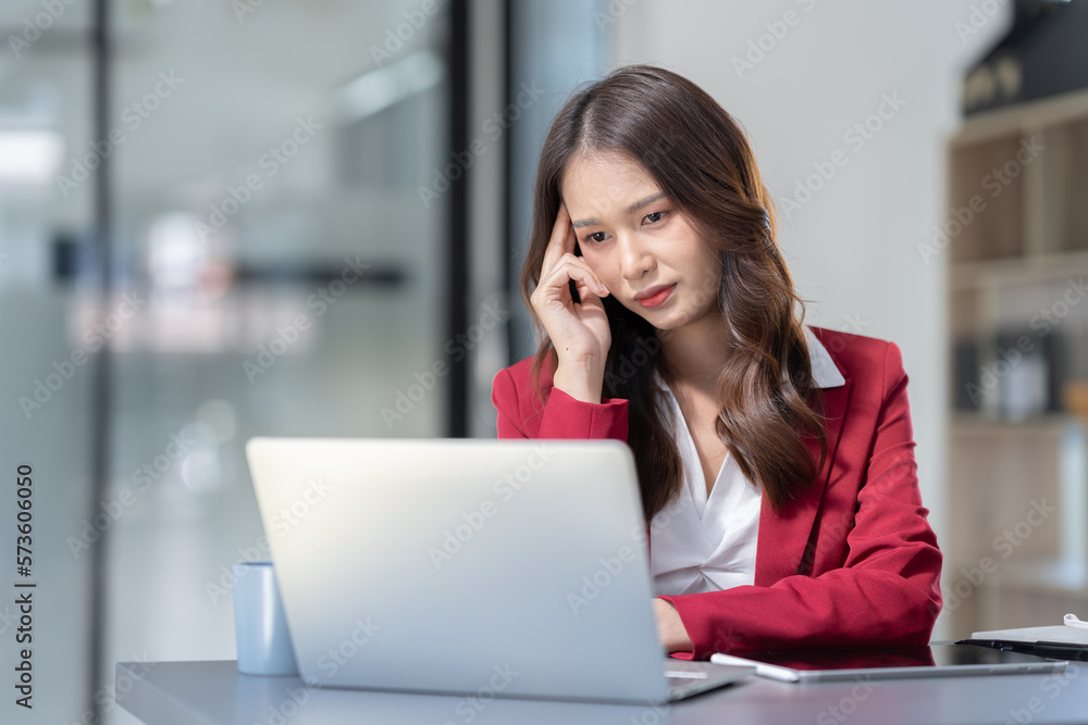 Asian businesswoman sitting in office stressed and fatigued from overwork on financial matters on office desk. Asian businesswoman sitting in office stressed and fatigued from overwork on financial matters on office desk.