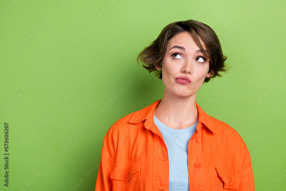 Photo of pretty lovely minded lady wear bright orange trendy clothes suspiciously look empty space isolated on green color background Photo of pretty lovely minded lady wear bright orange trendy clothes suspiciously look empty space isolated on green color background