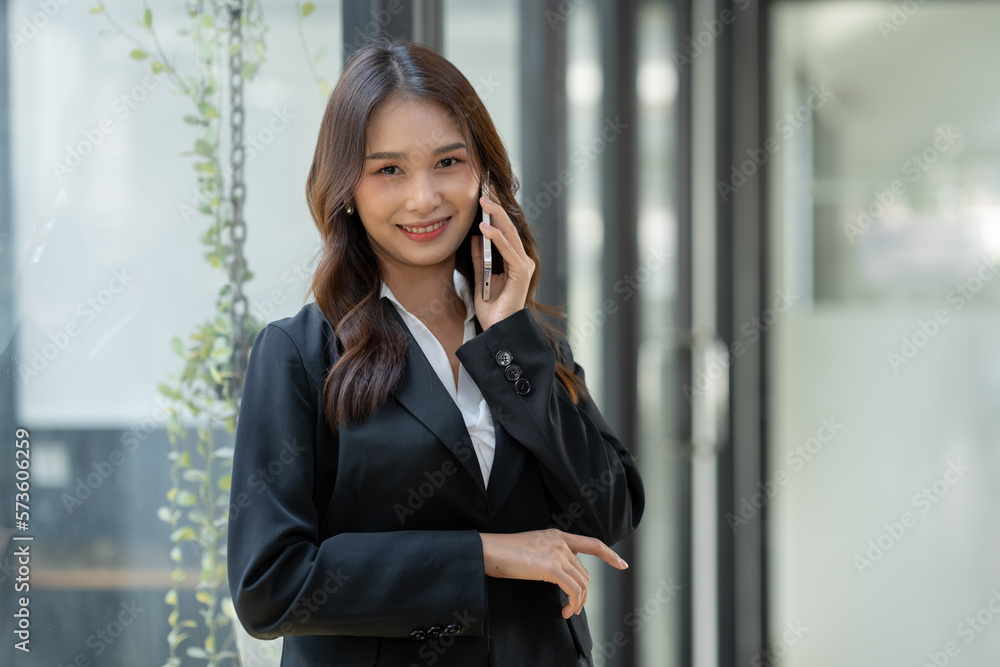Attractive Asian businesswoman using a mobile phone at the office for making contact Talk about online business. and financial income happily. Attractive Asian businesswoman using a mobile phone at the office for making contact Talk about online business. and financial income happily.
