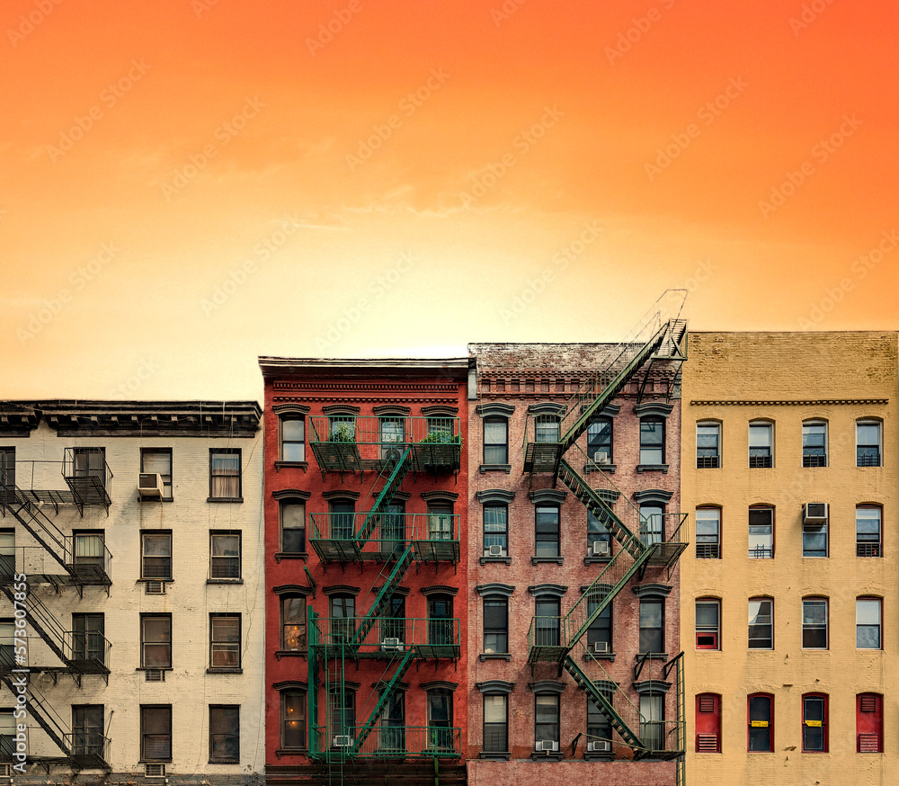 Row of colorful old apartment buildings in Manhattan, New York City with warm yellow orange sunset sky background